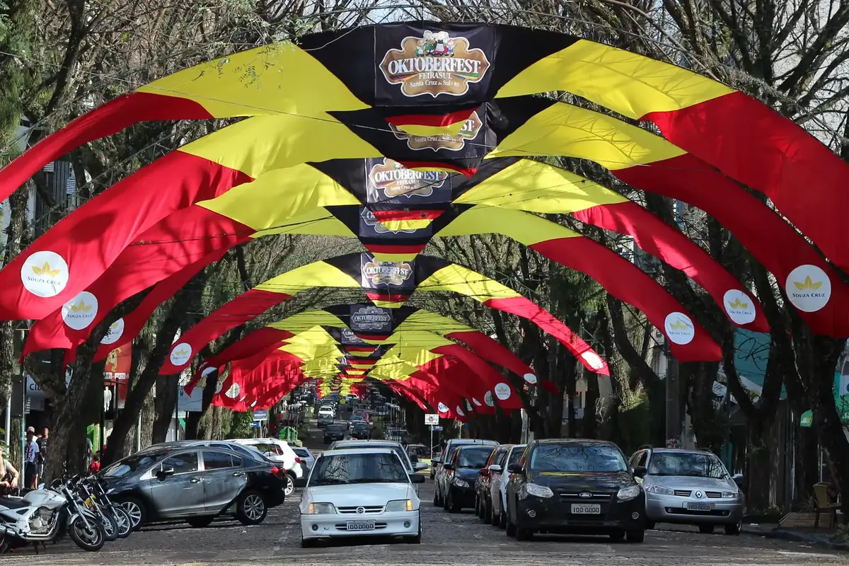 Avenida de Santa Cruz do Sul enfeitada com arcos da Oktoberfest e carros passando (Santa Cruz do Sul)